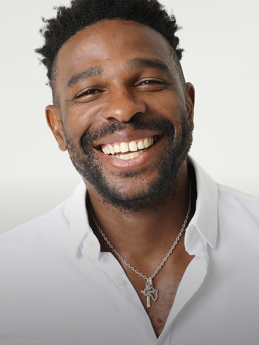 Smiling man wearing a necklace, white shirt.